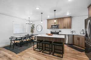 Kitchen featuring stainless steel appliances, wood finish cabinetry, a center island, and a breakfast bar area
