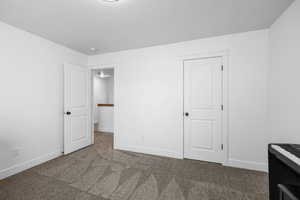 Unfurnished bedroom with baseboards and dark colored carpet