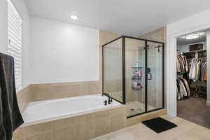 Full bath with a spacious closet, a stall shower, a bath, tile patterned flooring, and carpet floors