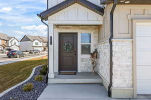 Doorway to property featuring stone siding, board and batten siding, a residential view, and a lawn