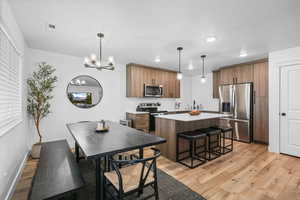 Kitchen featuring a kitchen island, light wood-style flooring, stainless steel appliances, and wood finish cabinetry