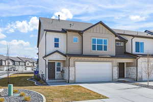 Craftsman inspired home with board and batten siding, stone siding, a shingled roof, and driveway
