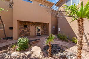 Rear view of property with stucco siding and stone siding