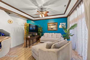 Living room with wood finished floors, crown molding, and a ceiling fan