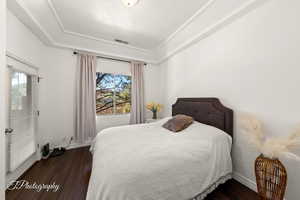 Bedroom with dark wood-style floors and a raised ceiling