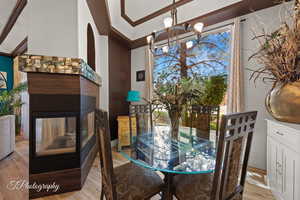 Dining space with suspended lighting, light wood-type flooring, and a multi sided fireplace