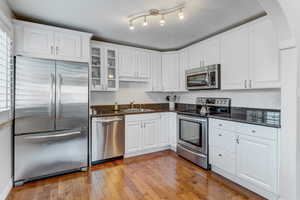 Kitchen with stainless steel appliances, glass fronted cabinets, white cabinetry, and Granite countertops