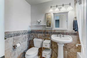Full bathroom featuring tile walls, a wainscoted wall, and a bathtub