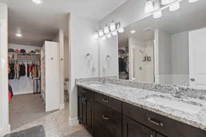 Full bath featuring a walk in closet, double vanity, recessed lighting, light tile patterned floors, and walk in shower
