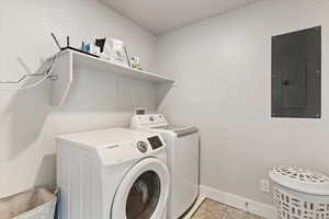 Laundry room featuring electric panel, independent washer and dryer, and light tile patterned flooring