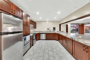 Community Kitchen featuring stainless steel appliances, light stone countertops, recessed lighting, and a peninsula