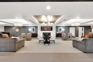 Community Living area featuring a chandelier, light carpet, and a raised ceiling