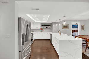 Kitchen with a peninsula, a kitchen breakfast bar, stainless steel appliances, white cabinets, and light stone counters