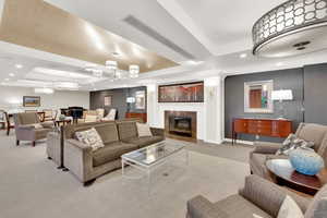 Community Carpeted living room featuring recessed lighting, wallpapered walls, a high end fireplace, and a tray ceiling