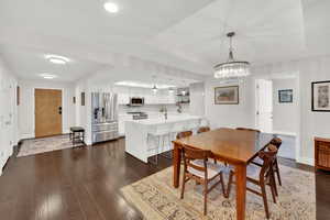Dining area featuring dark wood-type flooring, suspended lighting, and a tray ceiling