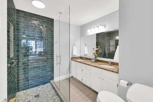 Guest Bathroom with double vanity, a stall shower, and light tile patterned floors