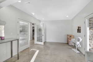 Interior space with finished concrete flooring, french doors, and recessed lighting