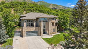 Prairie-style home featuring a mountain view, concrete driveway, a front yard, an attached garage, and a chimney