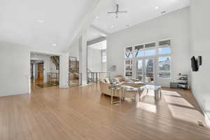 Living room featuring a ceiling fan, light wood-style flooring, a high ceiling, french doors, and recessed lighting