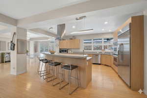 Kitchen featuring a breakfast bar area, stainless steel appliances, hanging light fixtures, and modern cabinets