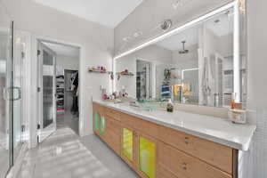 Full bath with a stall shower, double vanity, a walk in closet, and light tile patterned floors