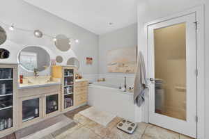 Full bath featuring vanity, a bath, and light tile patterned floors