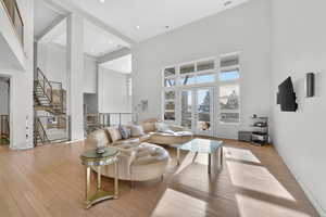 Living area featuring french doors, light wood-style flooring, a high ceiling, and recessed lighting