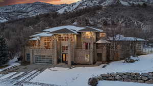 Prairie-style home featuring a balcony, a mountain view, stone siding, an attached garage, and stucco siding