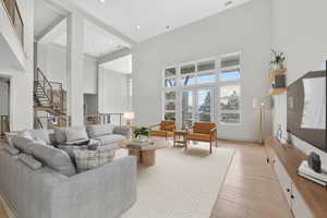 Living area featuring french doors, light wood-style floors, a high ceiling, and recessed lighting