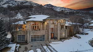 View of front of home with a mountain view, stone siding, stucco siding, a balcony, and a garage