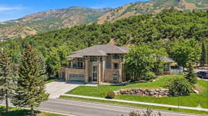 View of front of property featuring a front lawn, a mountain view, brick siding, and driveway