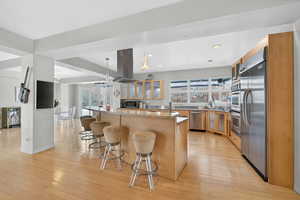 Kitchen featuring glass fronted cabinets, a breakfast bar, stainless steel appliances, hanging light fixtures, and a kitchen island