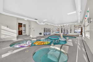 Indoor pool with a hot tub, a sunroom, and a skylight