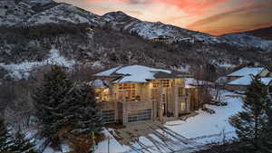 View of front of property featuring a mountain view, a patio area, an attached garage, stone siding, and a balcony