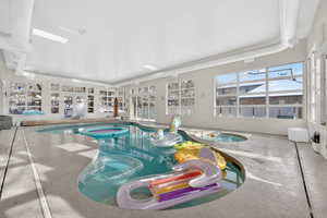 Indoor pool featuring a sunroom and an in-ground hot tub