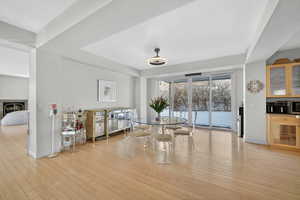 Dining area featuring a warm lit fireplace and light wood-style flooring