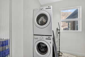 Laundry room featuring stacked washer / dryer and baseboards