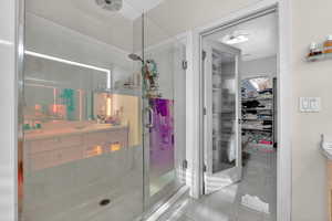Full bathroom featuring vanity, a stall shower, a walk in closet, and light tile patterned flooring