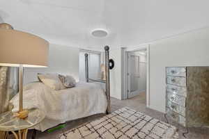 Bedroom with a textured ceiling and light colored carpet