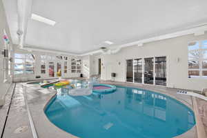 Indoor pool with a sunroom, french doors, a skylight, and a hot tub