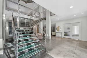 Stairway with finished concrete floors, french doors, and recessed lighting