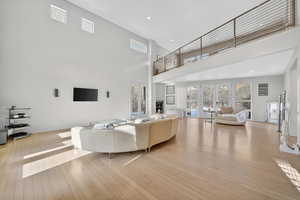 Living area with recessed lighting, light wood-type flooring, a high ceiling, and french doors