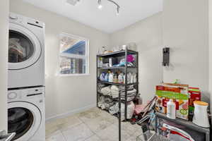 Laundry area featuring stacked washer and dryer and light tile patterned floors