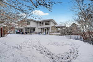 Snow covered property with a patio and stucco siding