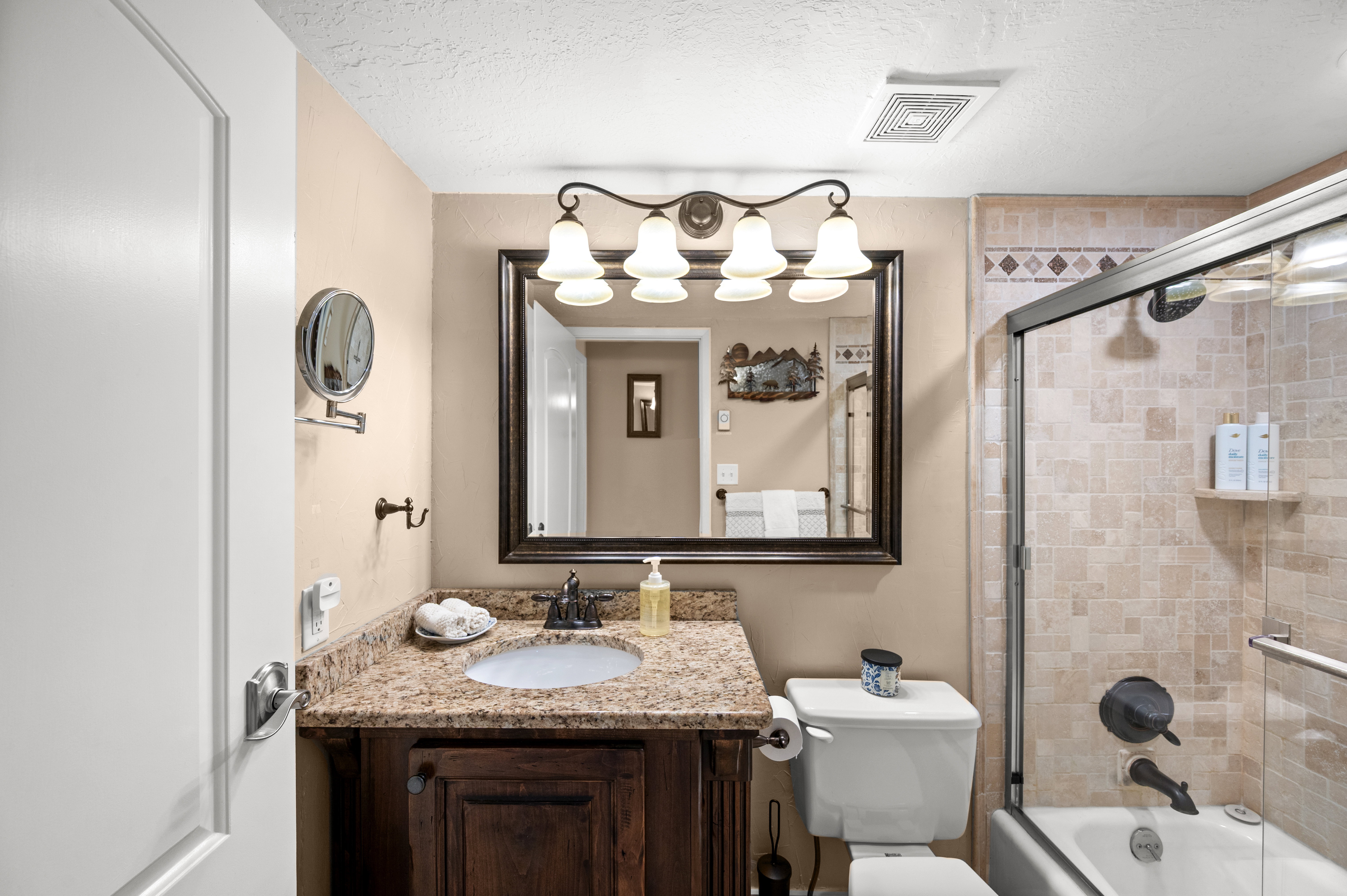 Bathroom with a textured ceiling, vanity, and shower / bath combination with glass door