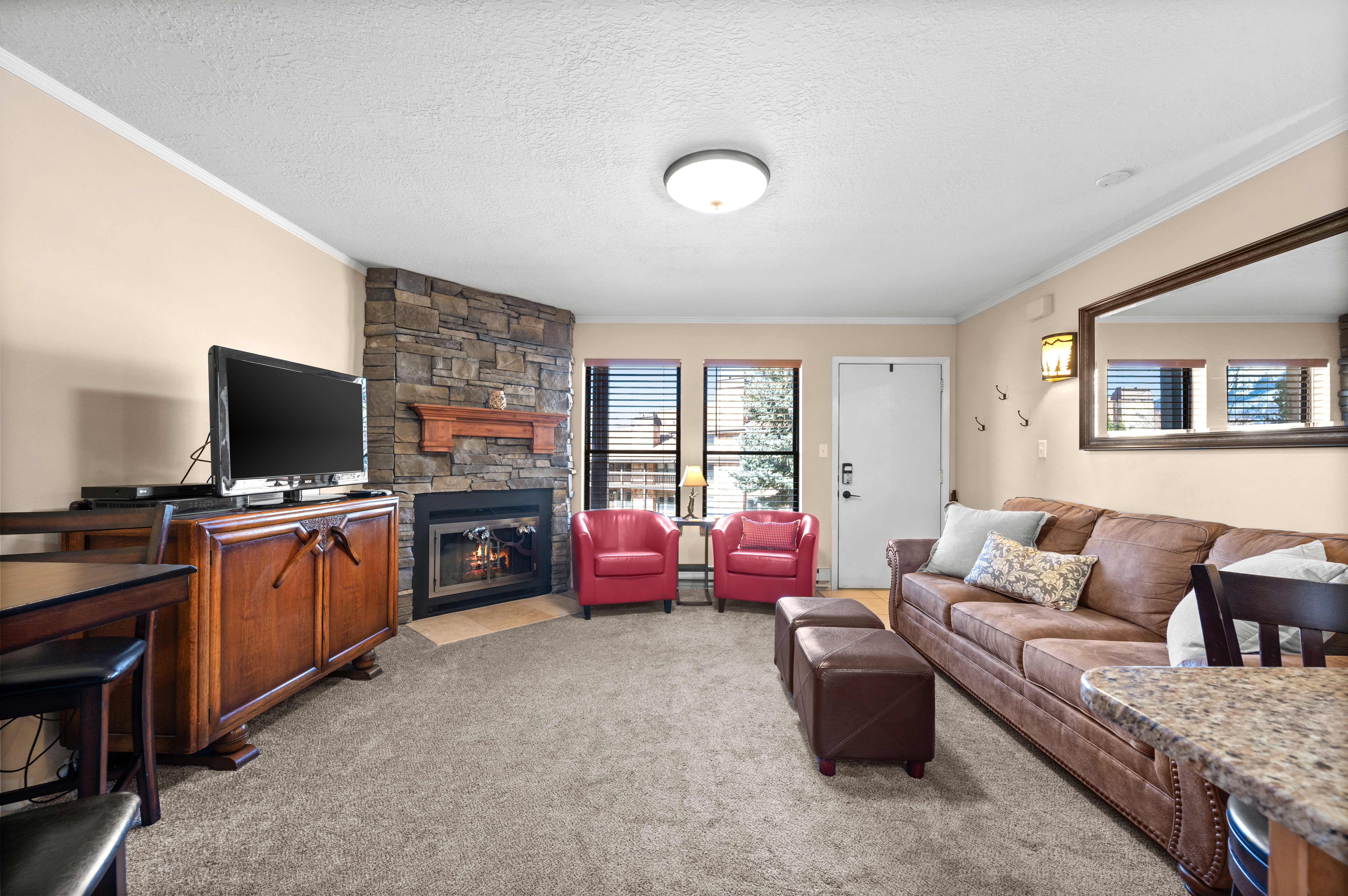 Living room with a fireplace, ornamental molding, light colored carpet, and a textured ceiling