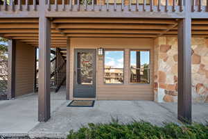 View of exterior entry featuring stone siding and a patio