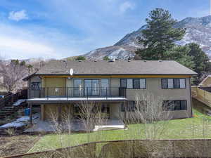 Back of property with a mountain view, stucco siding, roof with shingles, and a patio area