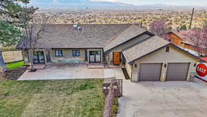 View of front facade featuring a shingled roof, french doors, stucco siding, a garage, and concrete driveway