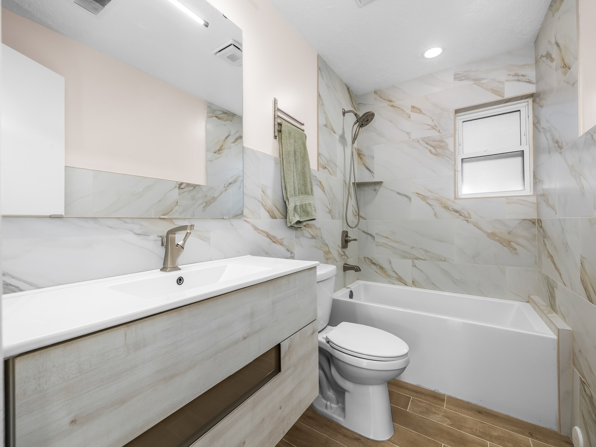 Full bath with vanity, bathing tub / shower combination, tile walls, and wood tiled floors